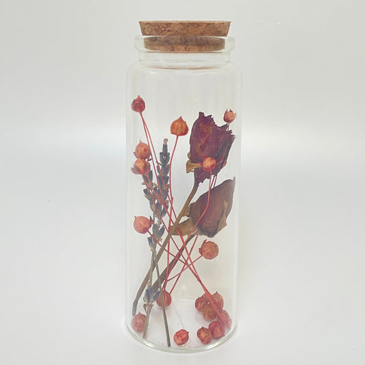 Test tube glass bottle filled with dried red roses and linum flax. 