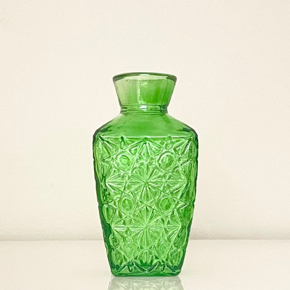 Green glass vase (F) with textured surface on a white background.