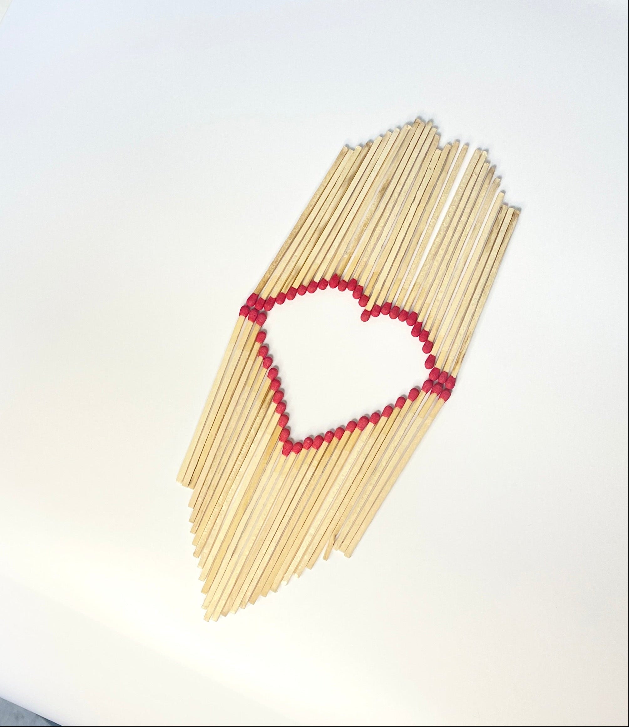 Matches arranged in the shape of a heart on a white background.