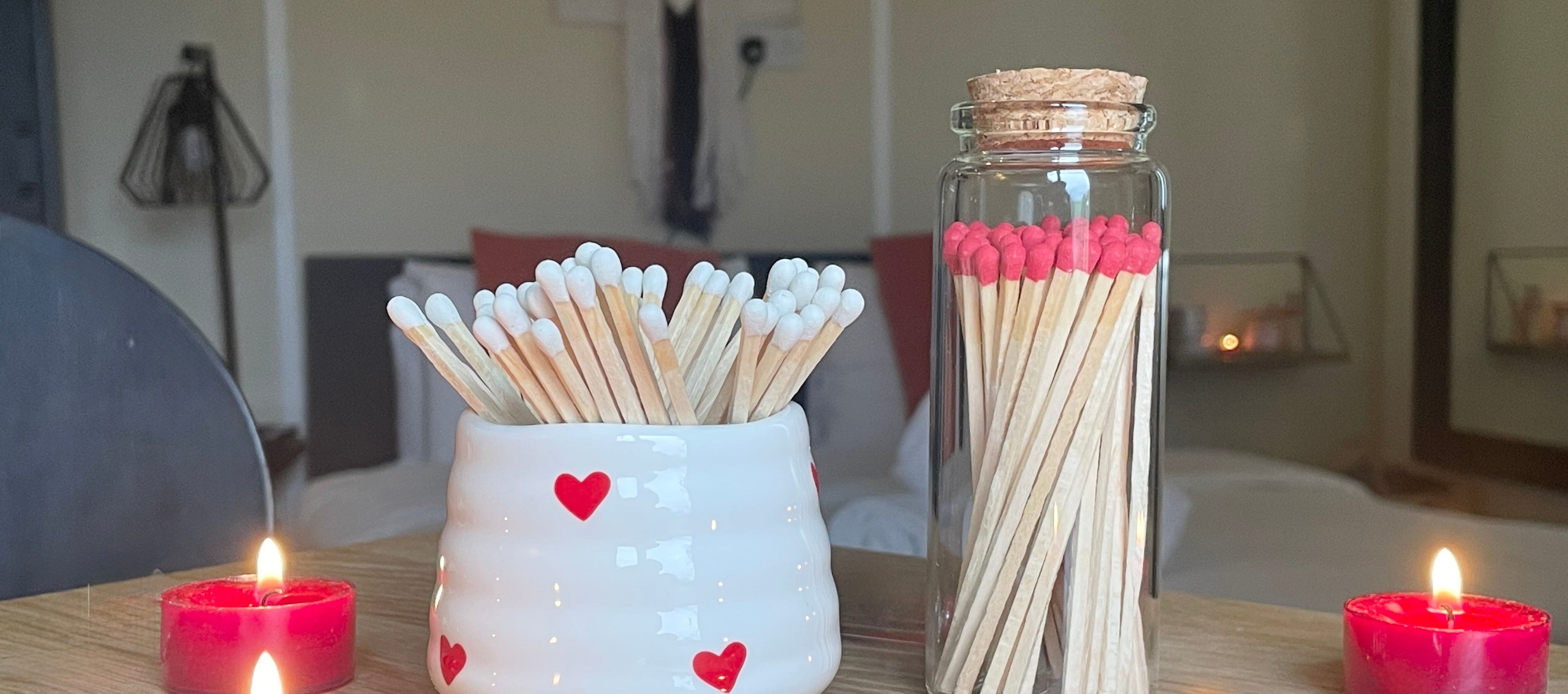 Matches in a jar and a match with heart designs on a table holder.