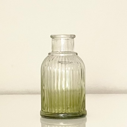 Green glass vase (C) with textured surface on a white background.