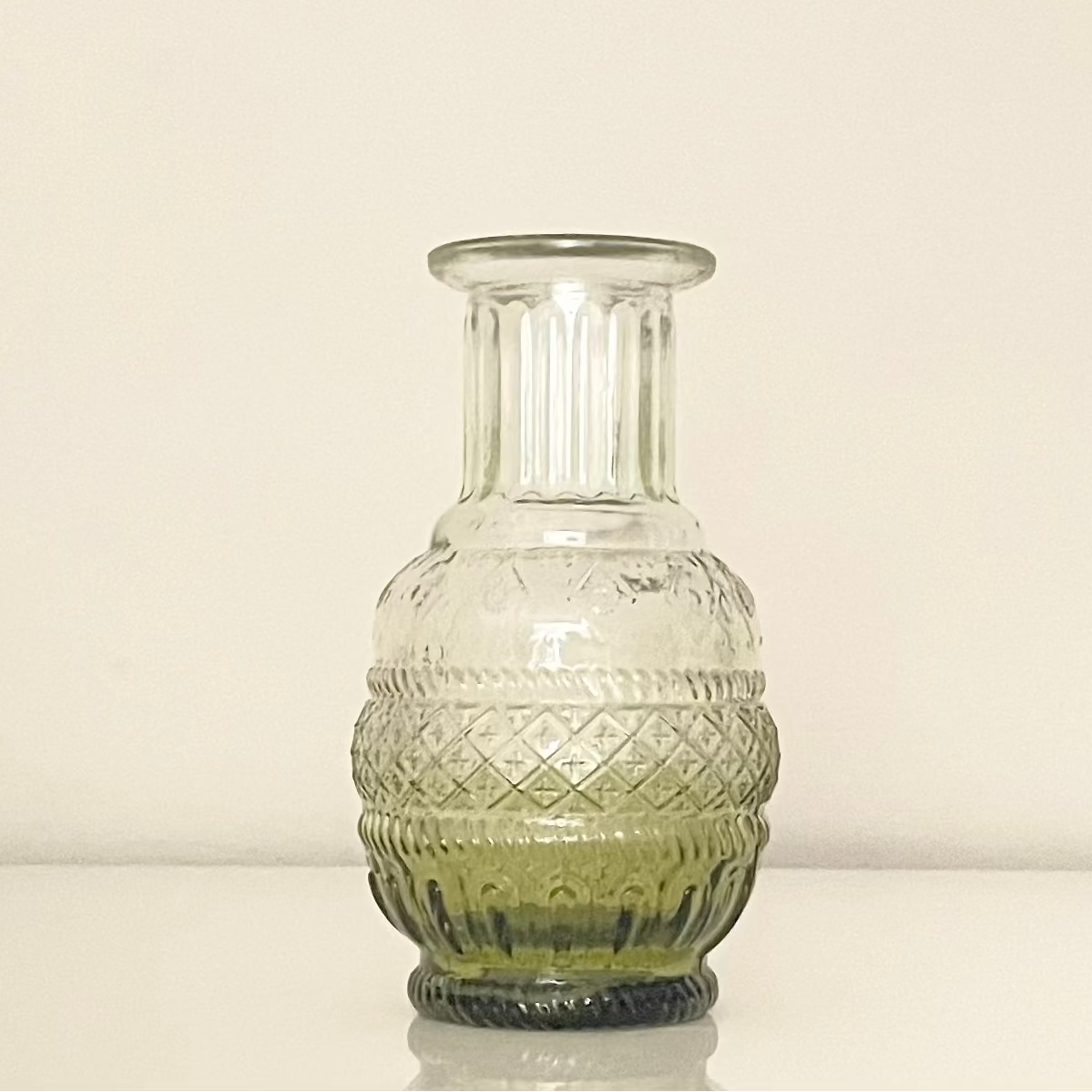 Green glass vase (A) with textured surface on a white background.