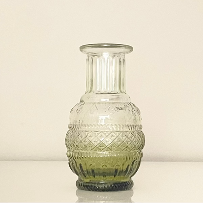 Green glass vase (A) with textured surface on a white background.