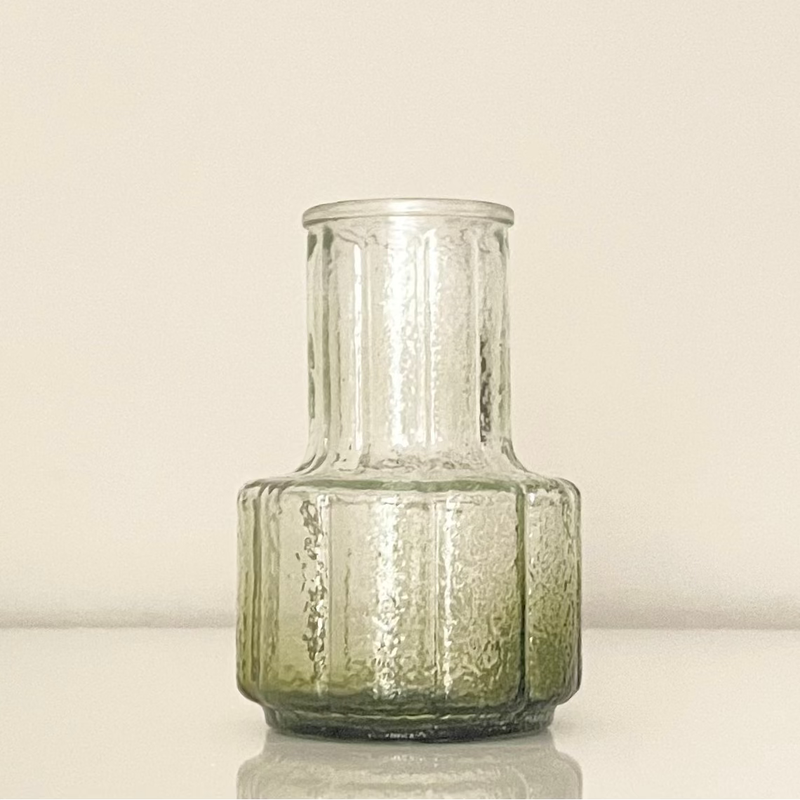 Green glass vase (B) with textured surface on a white background.