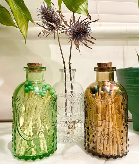 Vintage glass vases with corks, available in green, clear and amber. These multipurpose jars are perfect for holding matches (sold separately), storing small items, or to display fresh or dried flowers. 