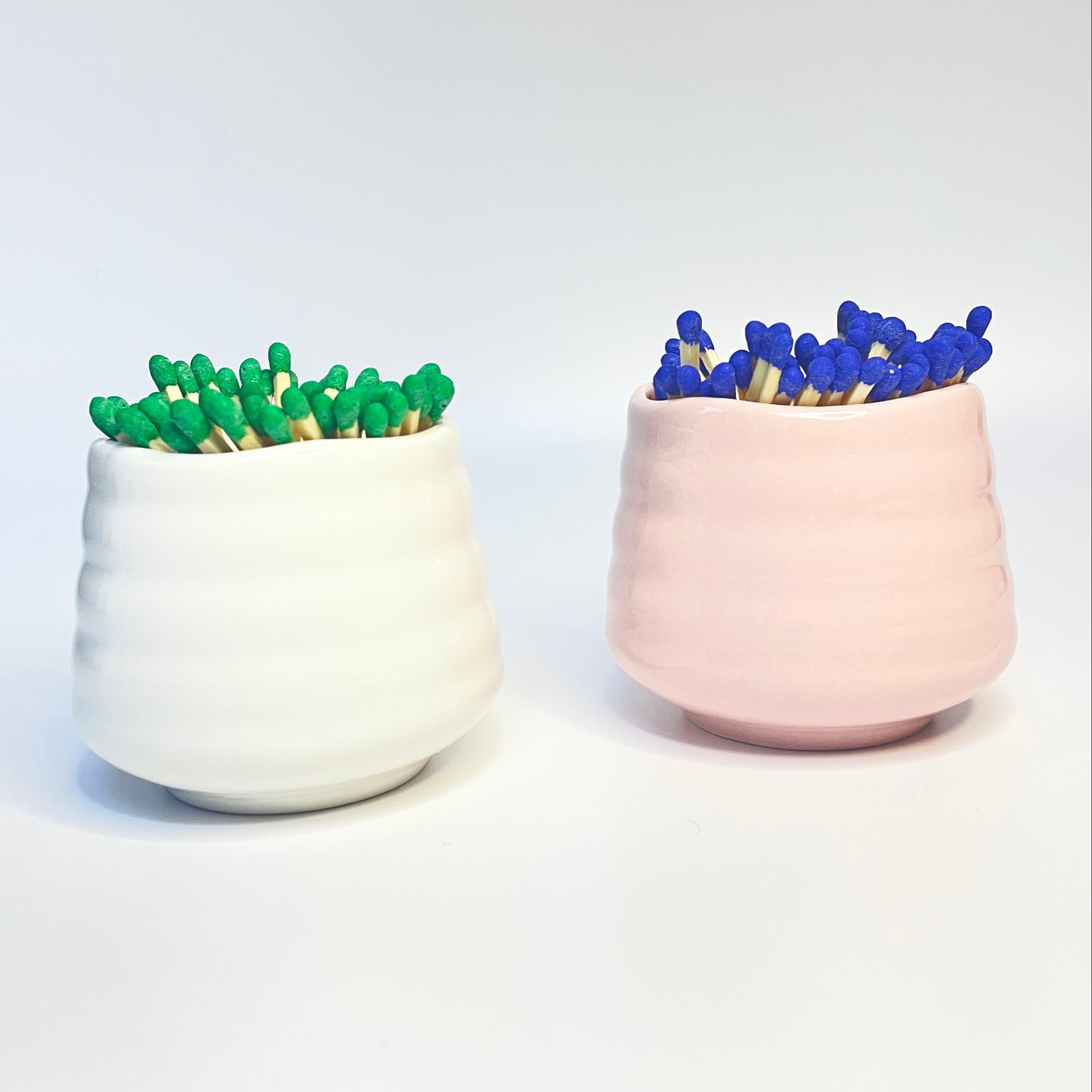 white and pink match holder/ coffee cups with green and blue coloured safety matches.