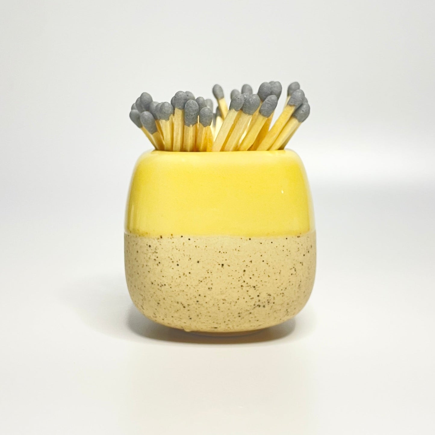 Yellow ceramic match holder on a white surface.