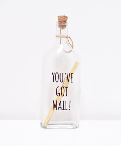 A glass bottle with a message "YOU'VE GOT MAIL" and a cork lid, containing a scroll to write your personalised text.